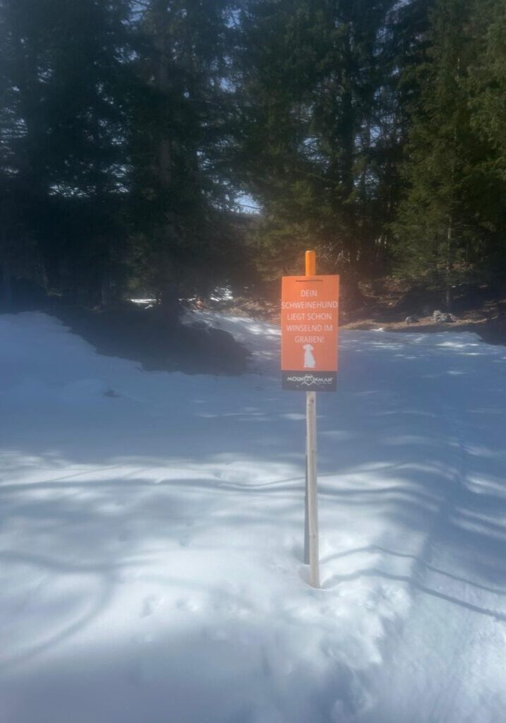 Schild "Dein Schweinehund winselnd im Graben!" im Schnee auf dem Mountainman Winter Trail Reit i. Winkel. - We Run 4 Fun!