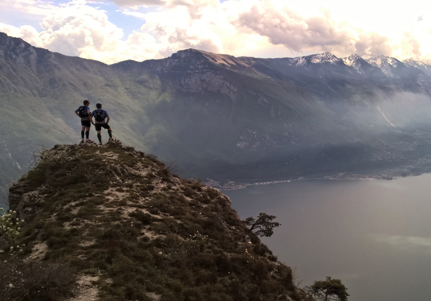 Zwei Läufer genießen die Aussicht am Gardasee beim Trail Running in den Bergen. - We Run 4 Fun!